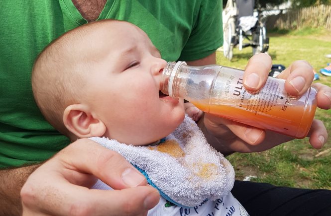bébé boit à la bouteille du jus orange fraise, pas de problème